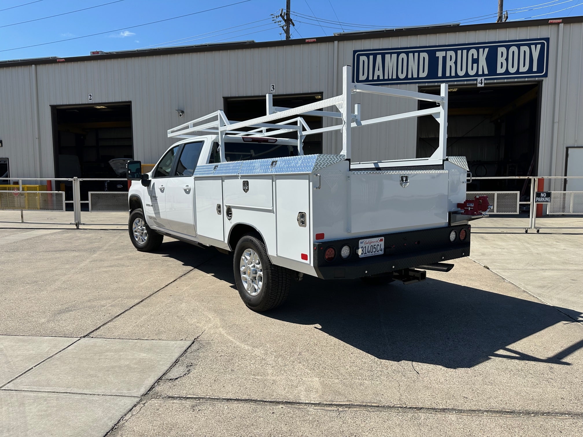 Custom white steel service body on Chevy 3500 with ladder rack and pull-out drawers