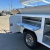 9-foot Diamond service body mounted on a 2026 Ford F-450 60-inch CA chassis, painted white with open-top compartments and aluminum diamond overlay lids.” WITH WORK SURFACE ON DROP DOWN DOORS
